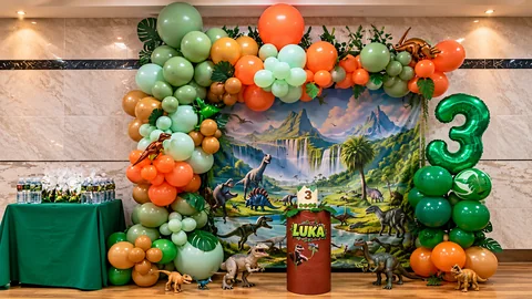 Decoración de dinosaurios con globos verdes y naranjas